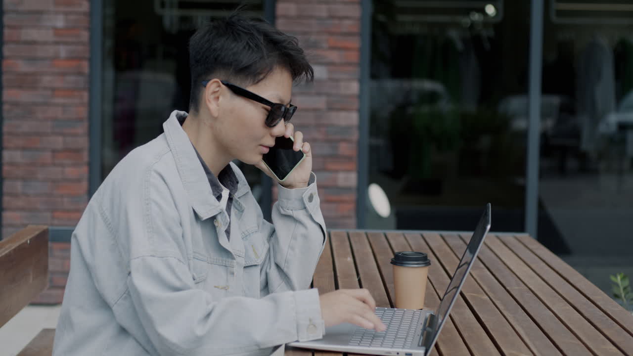 Person working outdoors at a cafe while talking on a phone