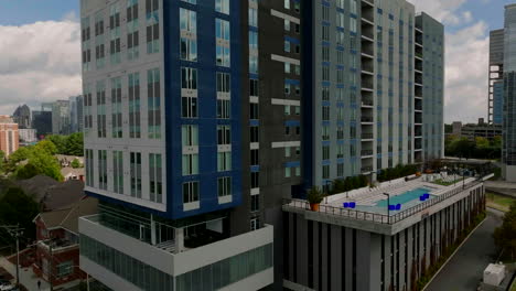 aerial slide and pan footage of modern apartment building with terrace and outdoor swimming pool