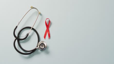 Video-of-stethoscope-and-red-blood-cancer-ribbon-on-pale-blue-background