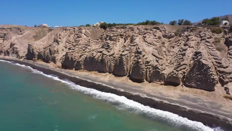 Luftflug-über-Griechische-Insel,-Felsige-Felsberge-Und-Blaue-Wasserwellen-Im-Mittelmeer-Am-Weißen-Strand-In-Santorini,-Griechenland