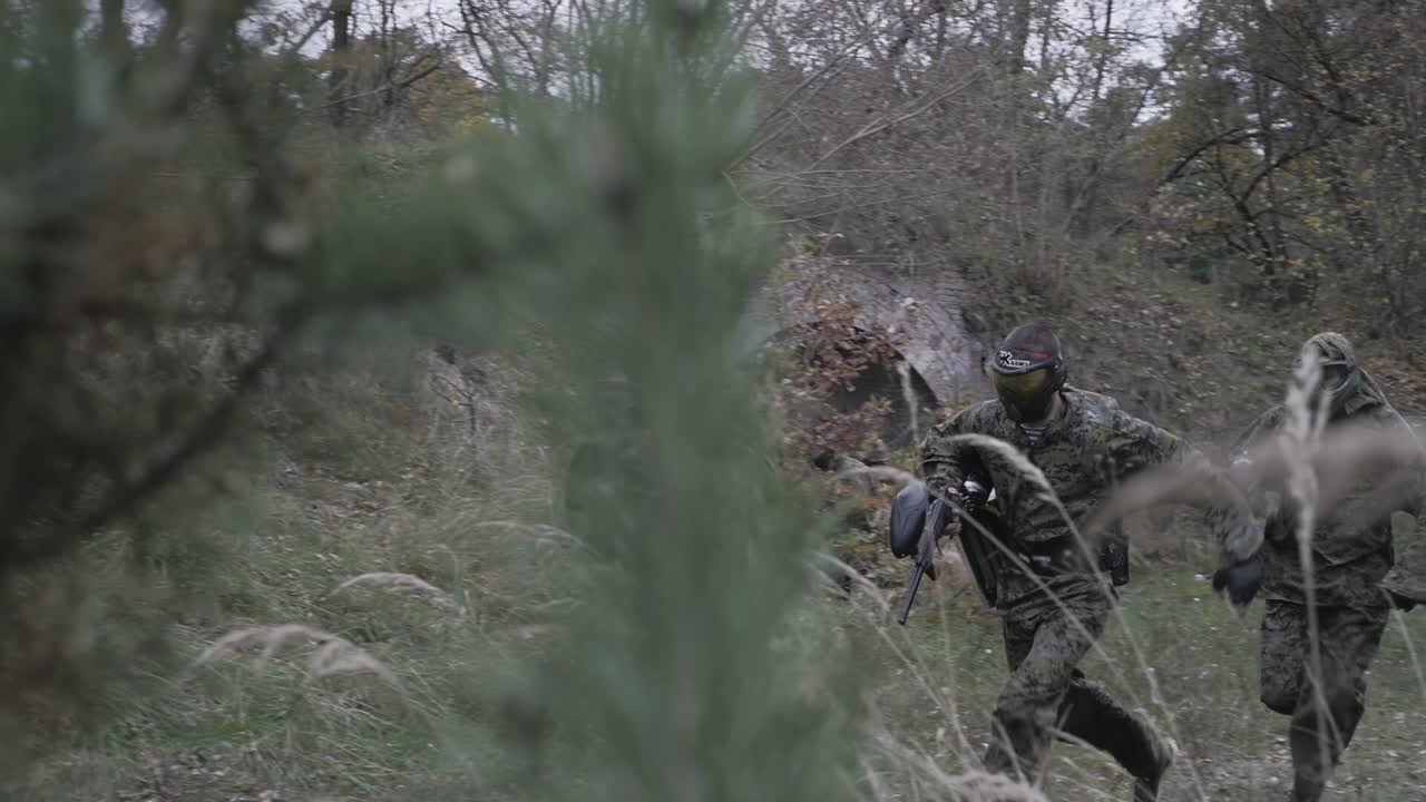 Giocatori di paintball corrono nella foresta al rallentatore