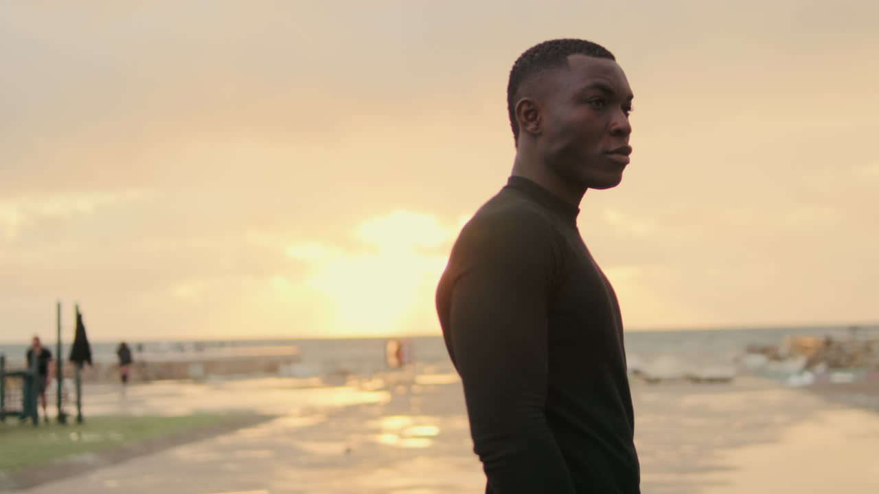 Young Black Man Standing by the Ocean at Sunset
