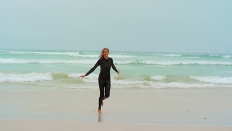 front view of active senior african american female surfer running on the beach 4k