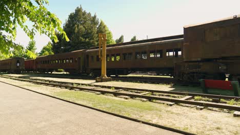 Schwenk-Nach-Rechts:-Panoramablick-Auf-Einen-Rostigen-Eisenbahnwaggon-Mit-Eisenbahnschienen-An-Einem-Sonnigen-Tag-In-Der-Ausstellung-Des-Eisenbahnmuseums-In-Temuco,-Chile