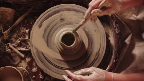 young woman potter working with a wet clay using brush and sponge