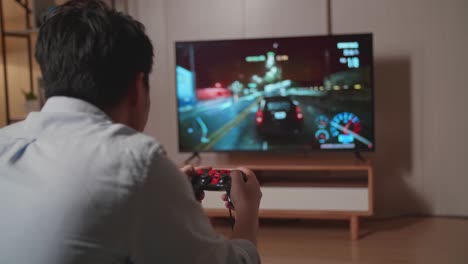 side view of young man gamer playing car race game on tv at home