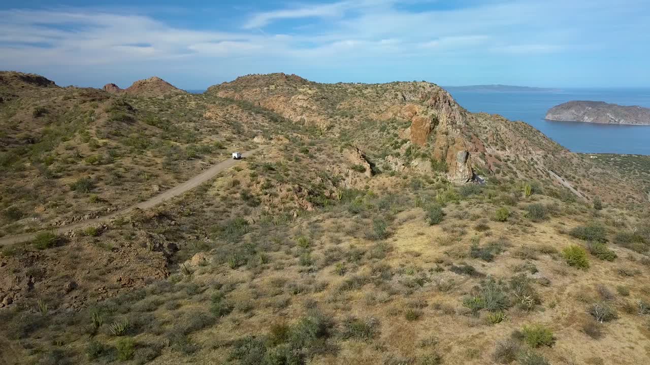 conducción de vehículos en una carretera escénica con un hermoso telón de fondo en el desierto tropical de méxico - toma de seguimiento de drones aéreos