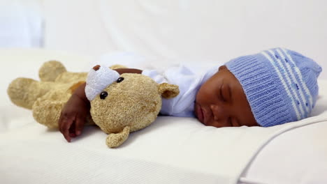 Baby-boy-sleeping-in-crib-with-teddy-bear