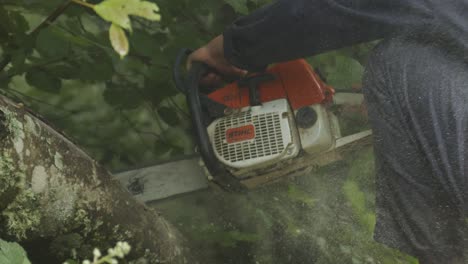 close up slow motion shot of a man cutting wood with a chainsaw