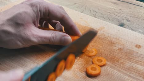 Slicing-fresh-carrots-on-a-wooden-cutting-board-with-a-very-sharp-knife