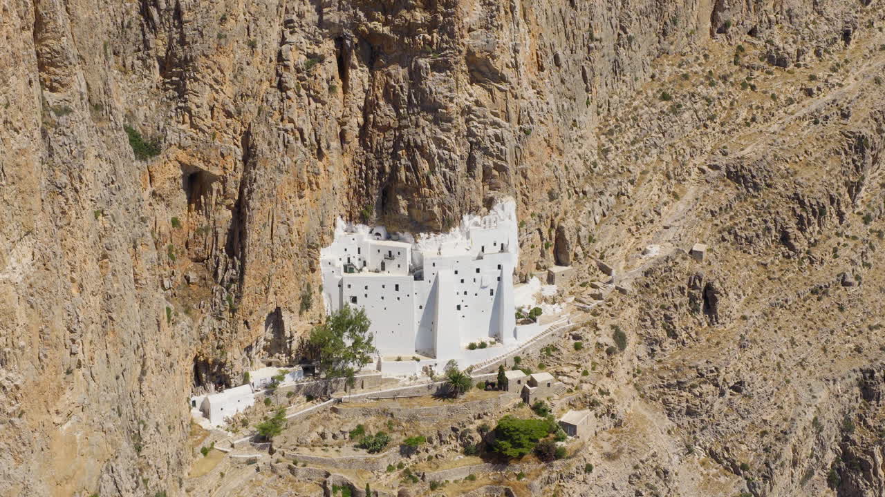 White Hozoviotissa Monastery built into steep cliffs, Amorgos Island, Greece, drone aerial medium closeup