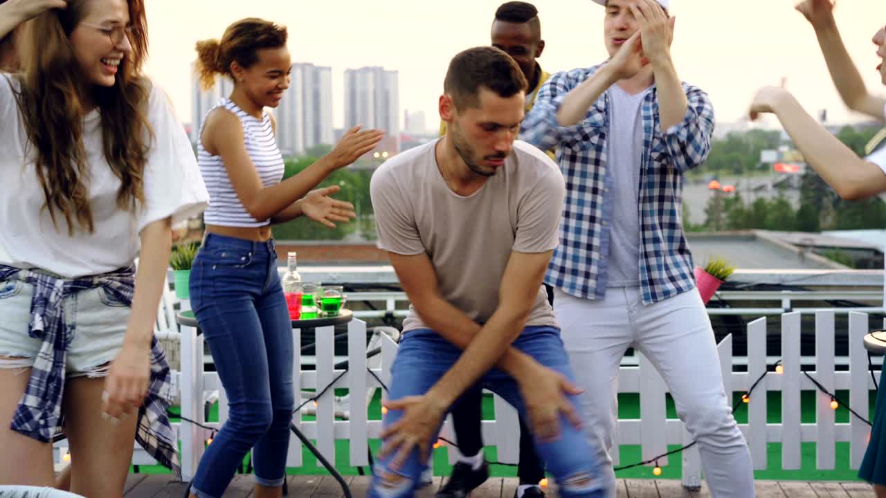un joven guapo está bailando en círculo de amigos divirtiéndose en la azotea en una fiesta al aire libre. celebración, estilo de vida activo y concepto de entretenimiento.