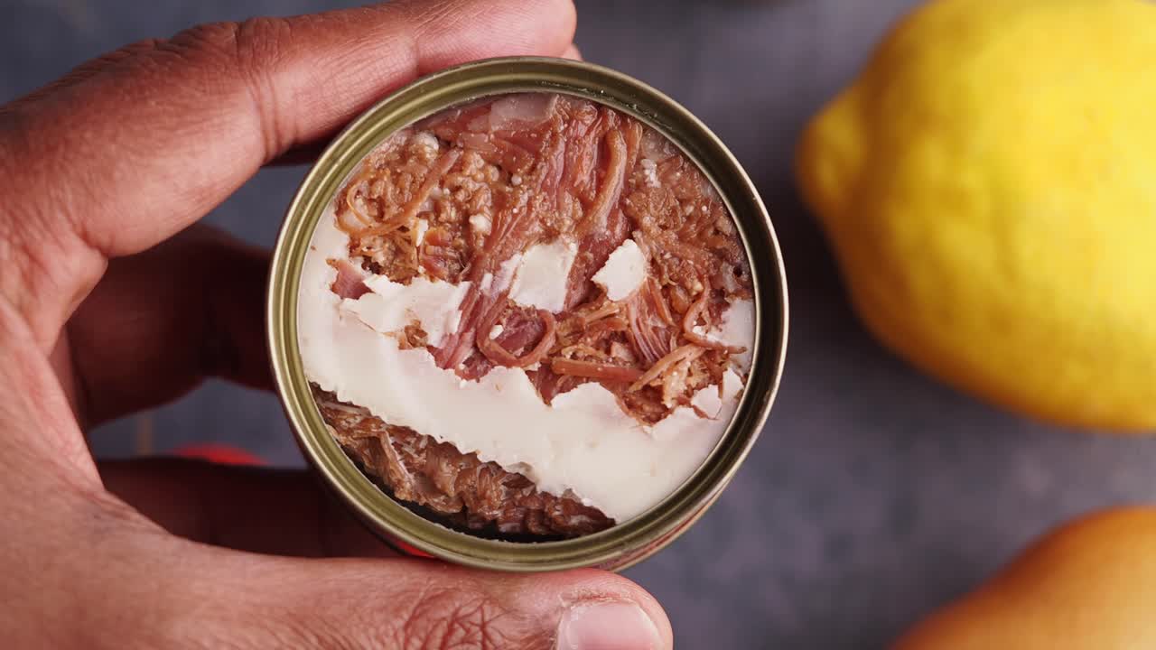 lata abierta de carne de res en la mano