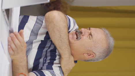 vídeo vertical de un trabajador de oficina en casa un anciano tiene dolor de hombro.