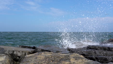 slow motion video of the waves from the ocean breaking over the rocks on the shore