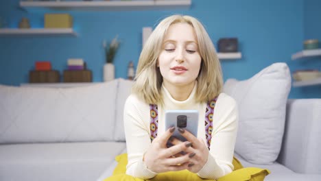 Junge-Blonde-Frau,-Die-Im-Liegen-SMS-Am-Telefon-Schreibt.