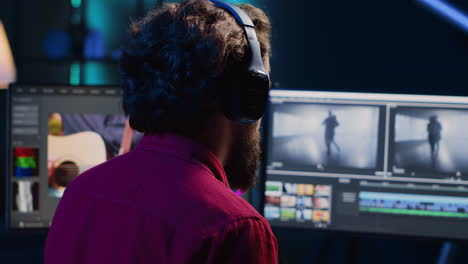empleado del estudio de postproducción trabajando con imágenes en bruto mientras escucha música en auriculares