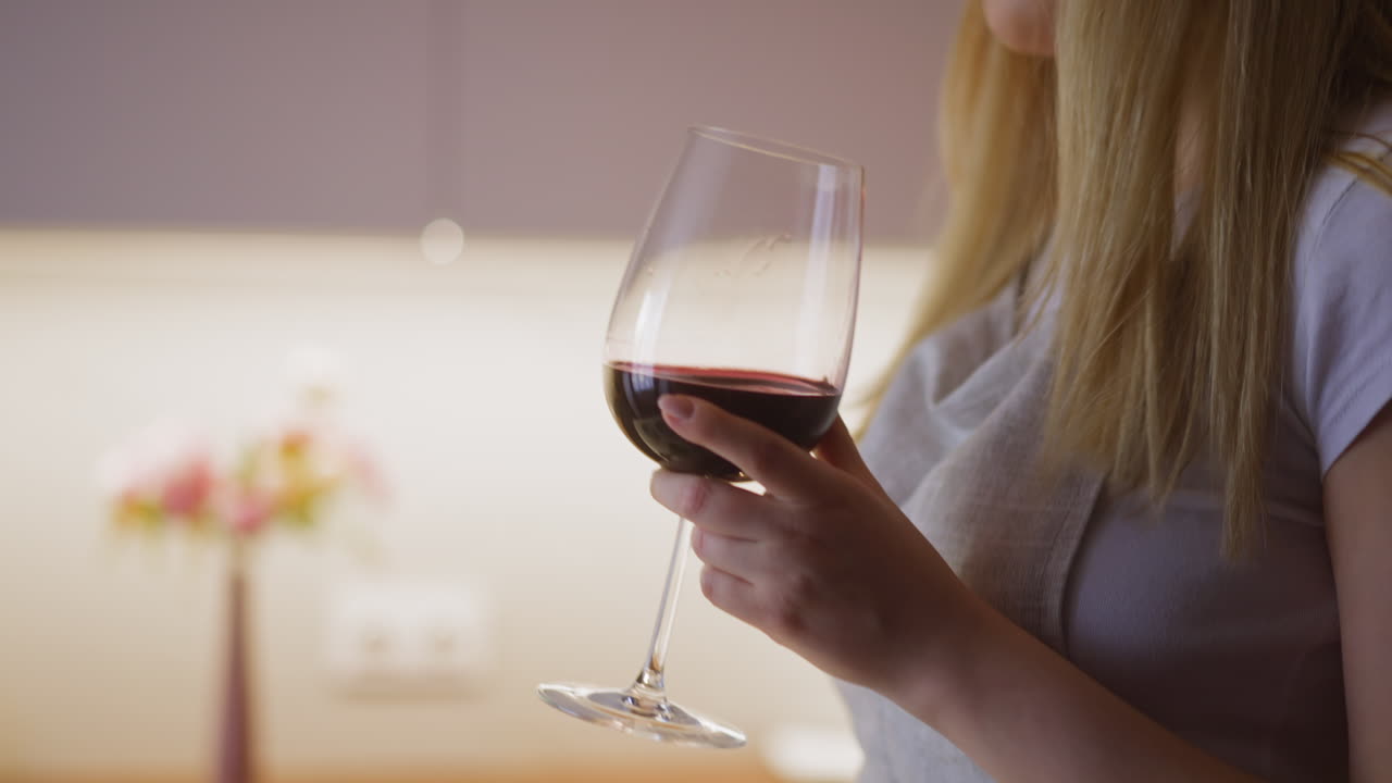 una donna beve vino rosso da collezione ballando mentre prepara il cibo