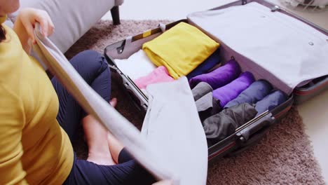 detail of female hands arranging clothes in takeout suitcase