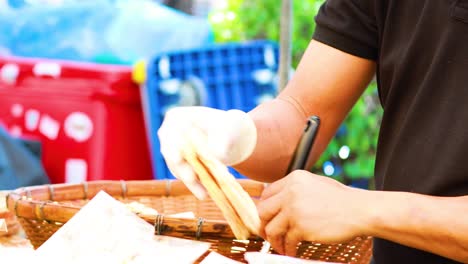 vendor prepares rice crackers with sauce topping