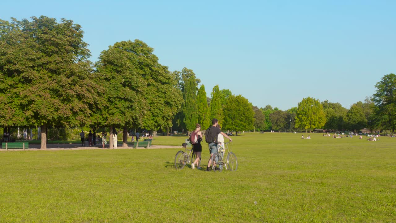 Friends walking with the bike in Golden Head Park in sunny day, Lyon