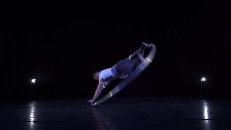 artista de circo muestra concentración y equilibrio mientras gira en una rueda de circo