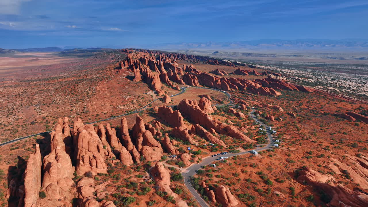Ridged rocks with rounded tops outlined by the highway. Scenic view on the the Arches National Park, Utah, USA from drone