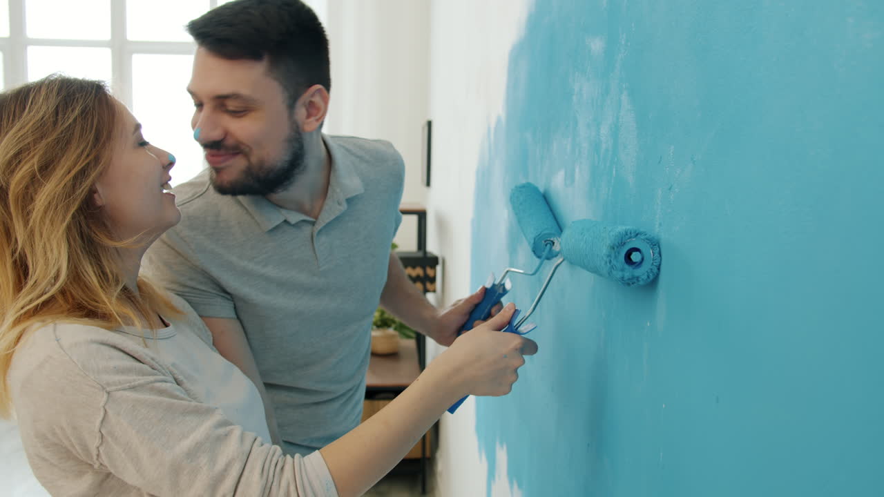 una pareja pintando una pared.