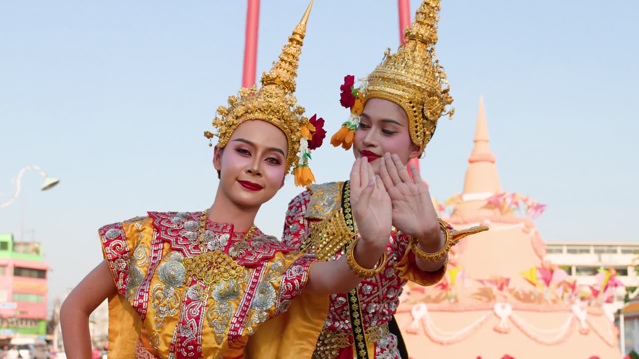 Ballerine in sontuosi costumi dorati eseguono movimenti tradizionali Khon all'aperto vicino alla Grande Altalena.