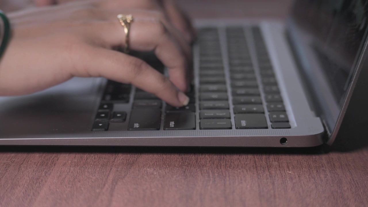 Close-Up of Hands Typing on a Silver Laptop.