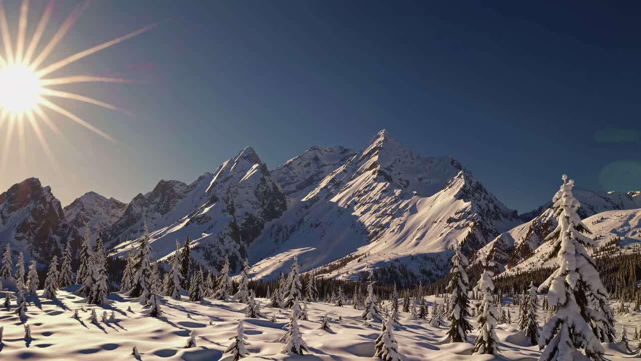 Aerial video captures snow-covered mountains and trees under a bright sun, showcasing a breathtaking