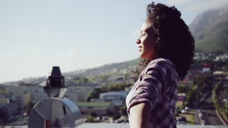 Fashionable-young-woman-on-urban-rooftop-with-arms-outstretched