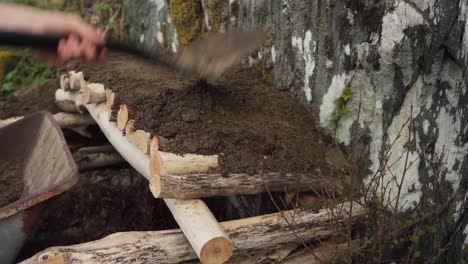 Man-Covering-The-Wood-With-Sand-Using-Shovel