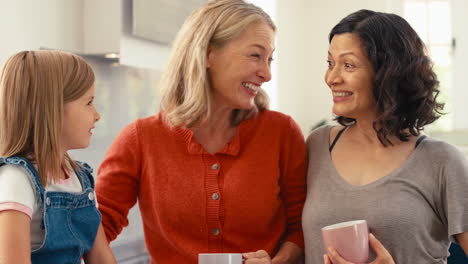 Same-Sex-Family-With-Two-Mature-Mums-And-Daughter-Sitting-In-Kitchen-Talking-Together