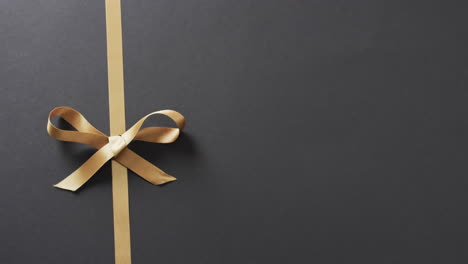 video of gold gift ribbon and bow with copy space on black background