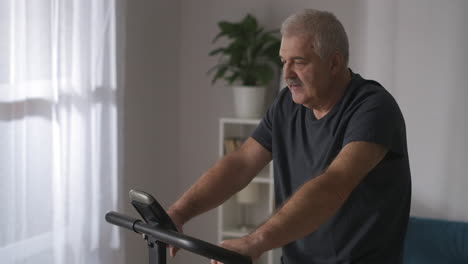 Retrato-De-Un-Hombre-De-Mediana-Edad-Entrenando-Con-Bicicleta-Estática-En-Casa-Preocupándose-Por-La-Salud-Manteniéndose-En-Forma-En-La-Actividad-Deportiva-De-La-Vejez