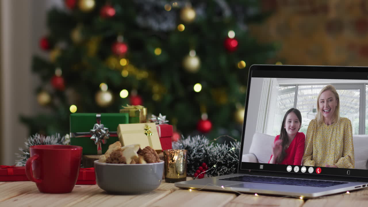 madre y hija felices en videollamada en computadora portátil, con decoraciones de navidad y árbol