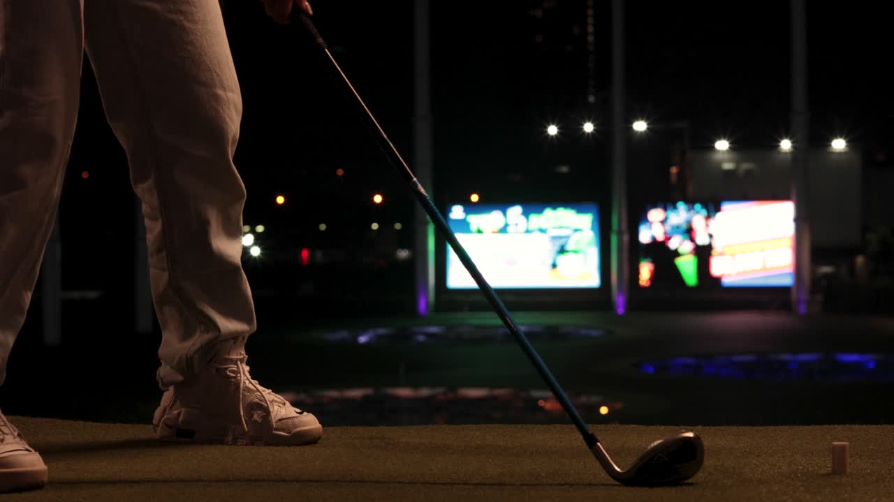 골퍼 가 조명 된 운전장 에서 스 을 연습 하고 있다