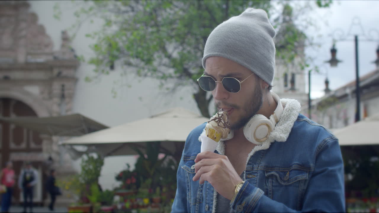 Ragazzo attraente che mangia un gelato per strada.