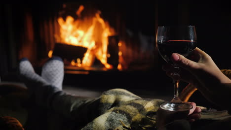 bask under a blanket by the fireplace with a glass of wine in his hand winter escape concept