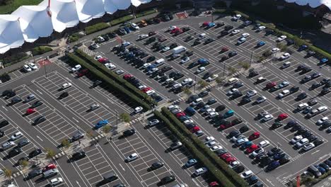 aerial view tracking a black car around a busy shopping car park