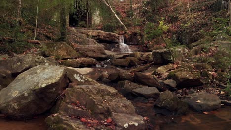 rocky creek falls leading to dark, overgrown tunnel