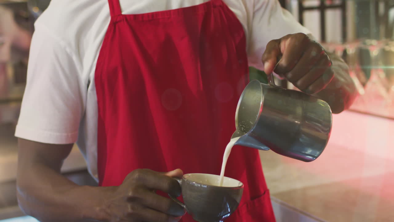 Animation of lens flare with male barista wearing mask preparing coffee at a cafe