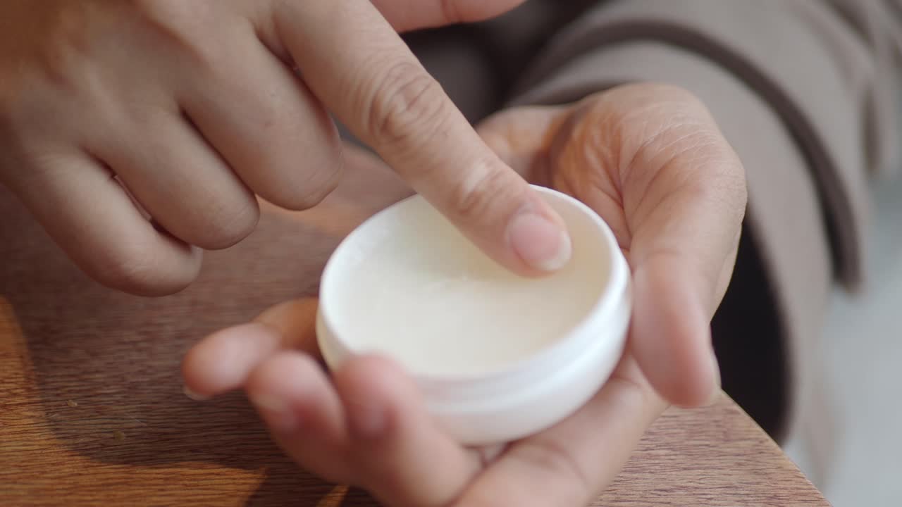 Primer plano de un dedo sumergiéndose en un recipiente de crema blanca