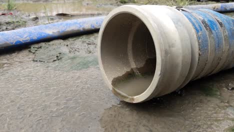 blue storm water hose, dripping and laying on a muddy ground