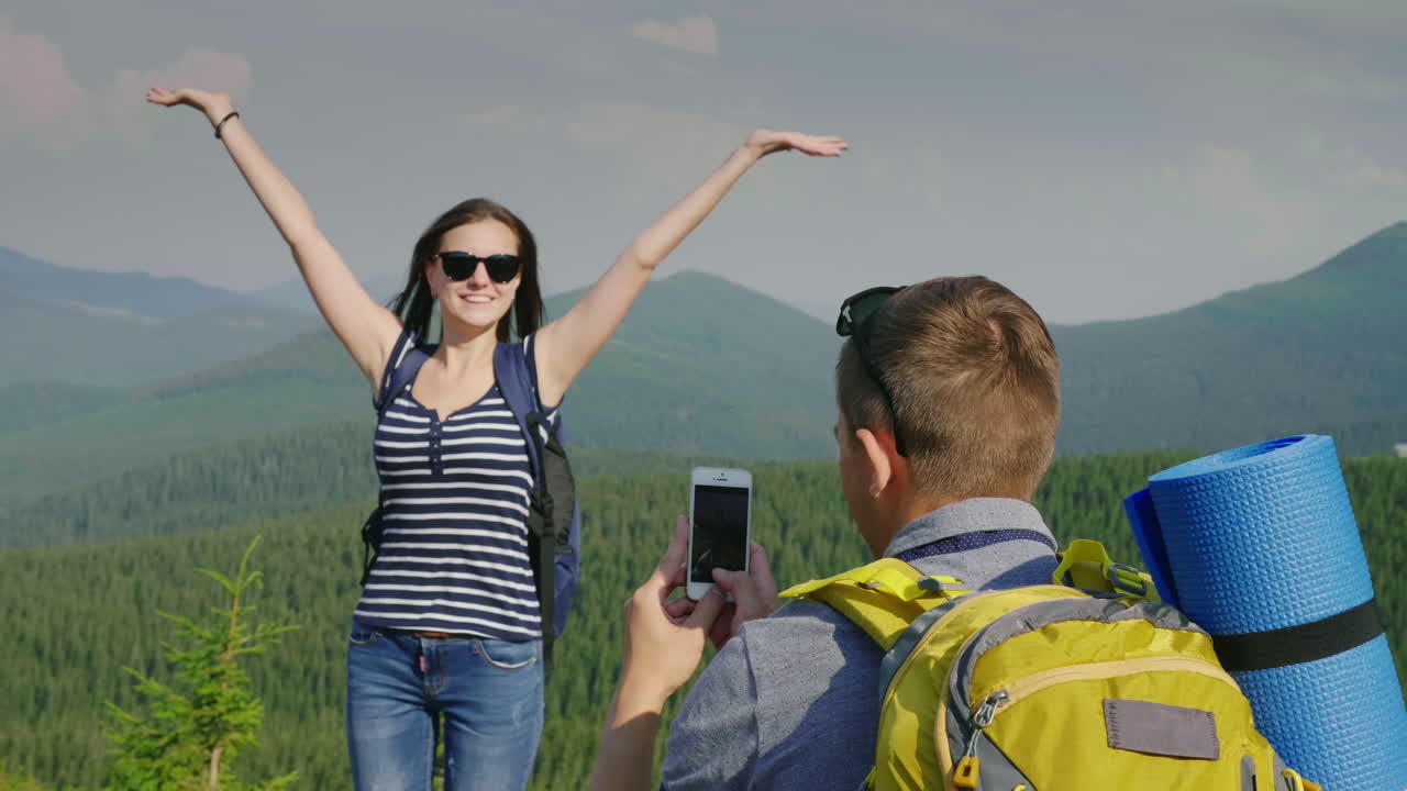 отдых в горах летом мужчина фотографирует свою девушку на красивом фоне