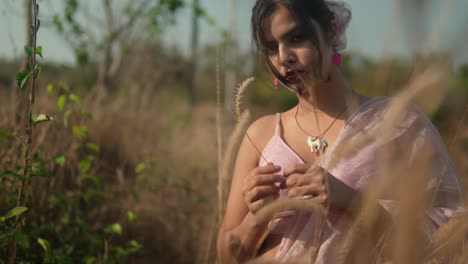 joven con vestido rosa en medio de la hierba seca, primer plano borroso, enfoque suave, tranquilo