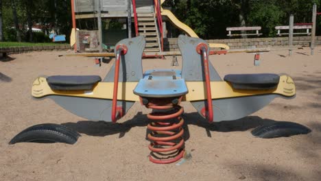 empty kindergarten swing swinging slowly on a playground in the town of partille outside of gothenburg, sweden