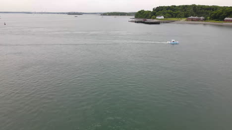 Luftflug-über-Wasser-Mit-Einem-Kleinen-Boot-In-Der-Mitte,-Das-Auf-Land-Zusteuert,-Drohne-Von-Rechts-Nach-Links