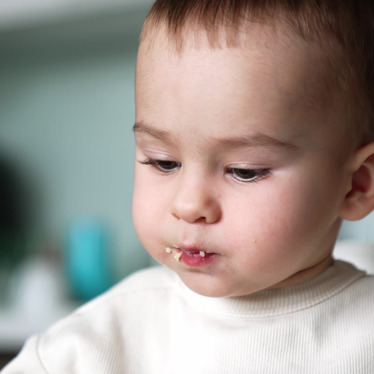Beautiful infant kid having meals. Child with smudged face close up. Baby boy is fed from spoon